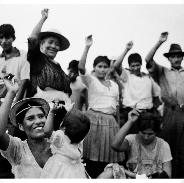 Villagers raising their arms and smiling, black and white