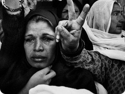 Woman making a peace sign in a crowd, black and white